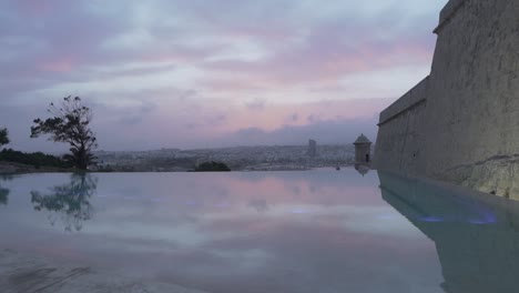 cloudy colourful sunset view over valletta grand harbour view from luxury infinity pool - slowmotion