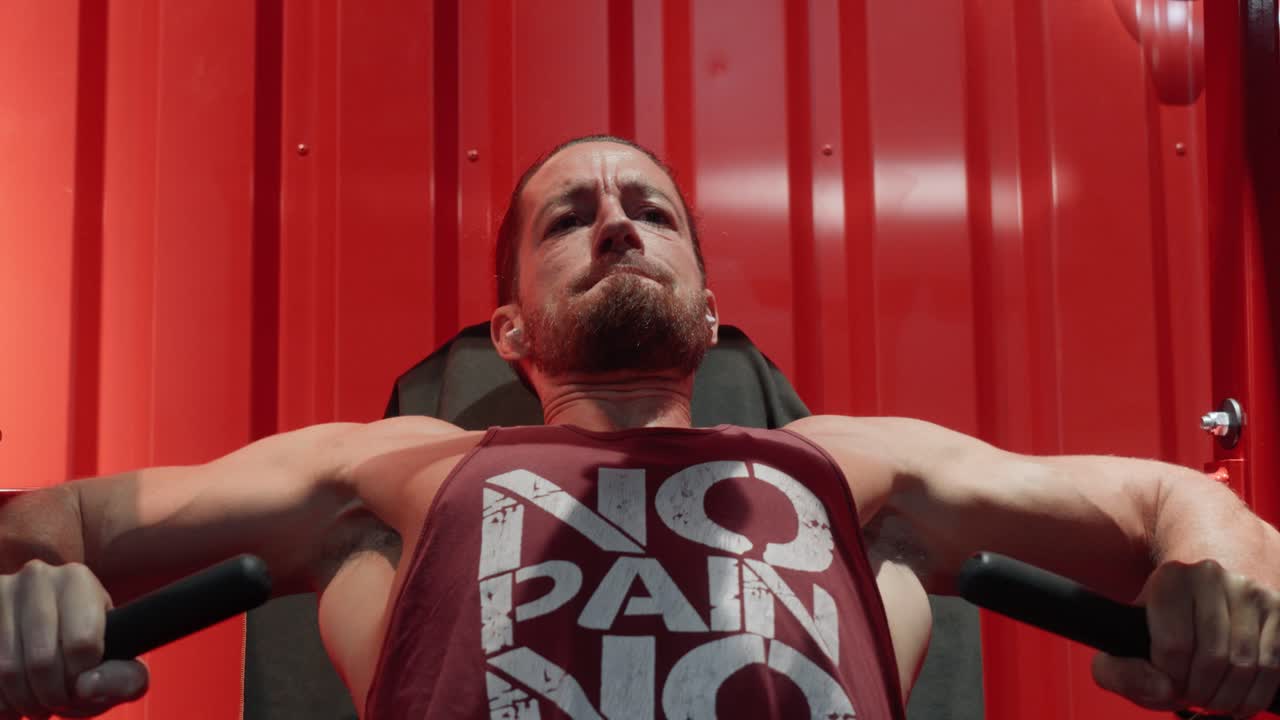 Atleta con dolor esforzándose por terminar su serie de press de banca inclinado en el gimnasio