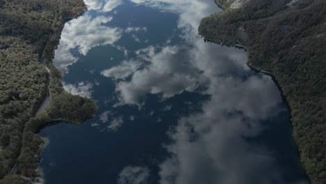 Reflejo-Perfecto-De-La-Nube-En-La-Superficie-Del-Agua-Del-Lago-En-El-Valle-Montañoso,-Barco-De-Recreo-Creando-Ondas,-Antena