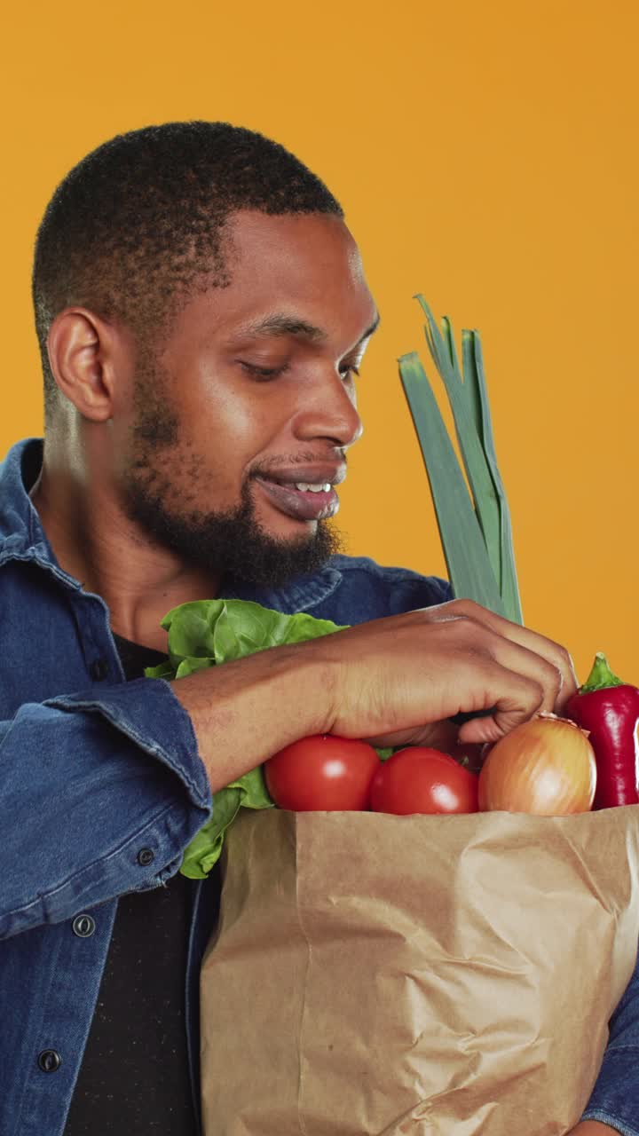 Homem feliz segurando uma sacola de papel cheia de vegetais frescos