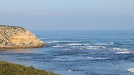 waves crashing against rocky coastal bluff at sunset