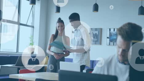 animation of profile icons floating over diverse man and woman discussing over documents at office