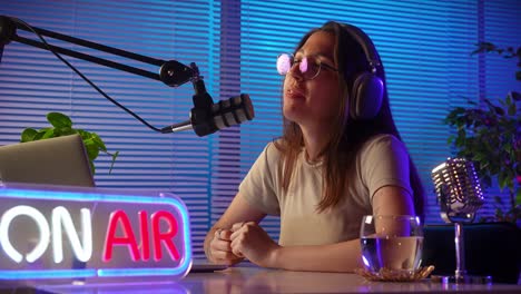 woman podcaster recording live broadcast in studio with "on air" sign
