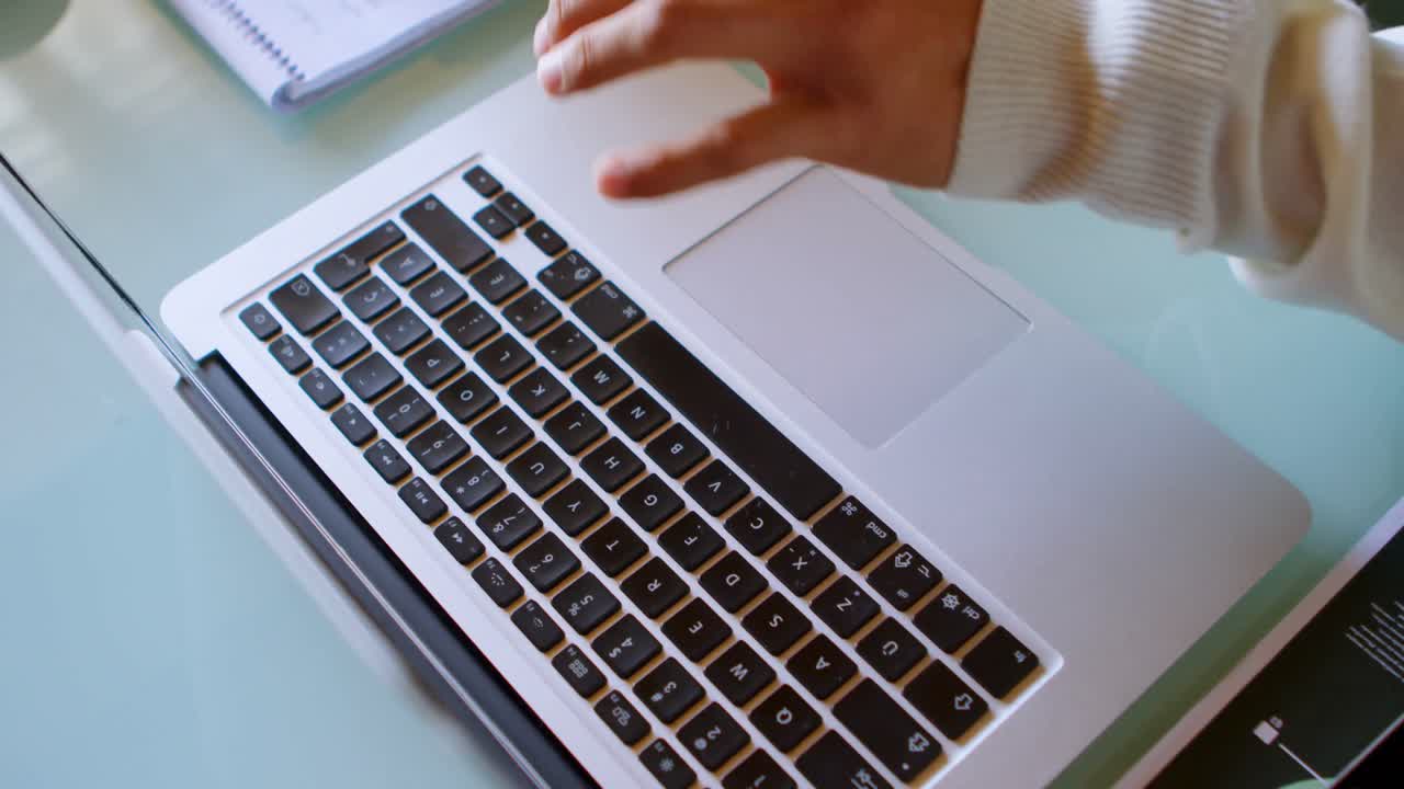 hombre escribiendo en el bloc de notas mientras usa una computadora portátil en casa 4k