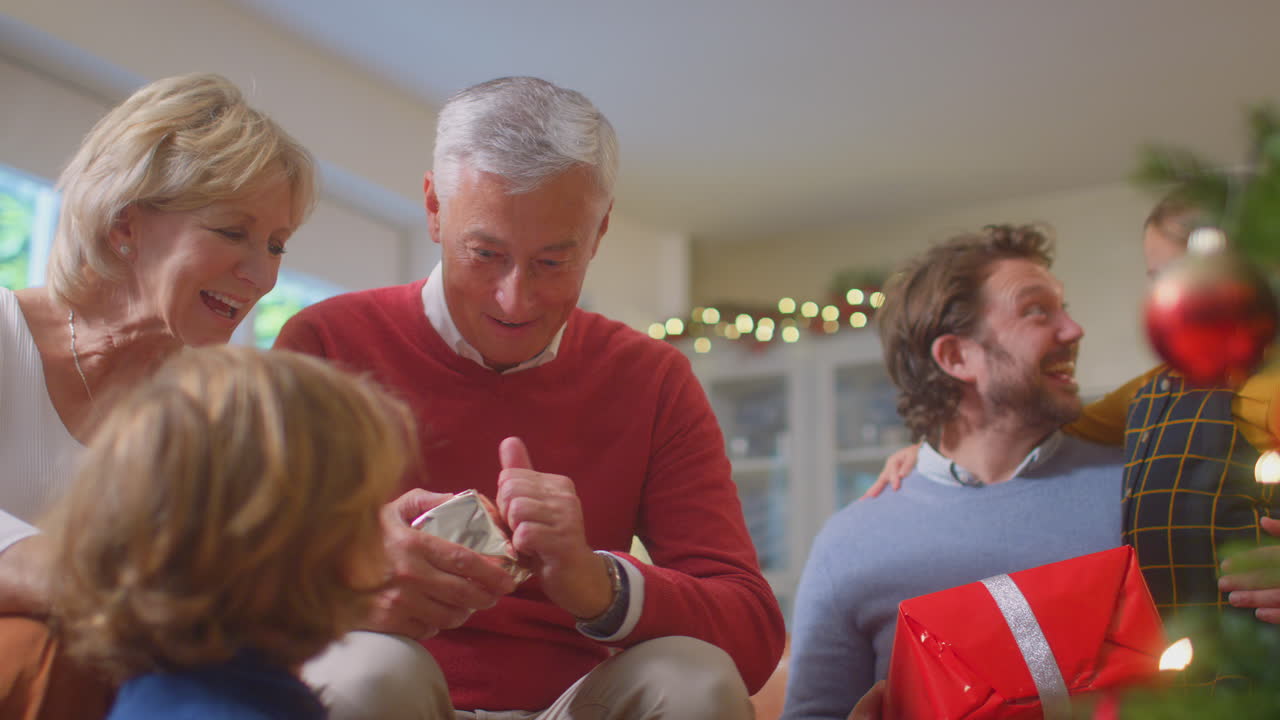 집 에서 크리스마스 트리 주위 에서 선물 을 교환 하고 열고 있는 다세대 가족