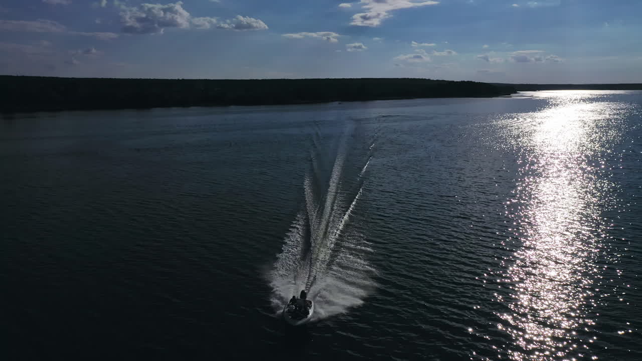Motor boat moves on water. Amazing view on a river and boat floating at beautiful silver path on water from the setting sun. Aerial view.