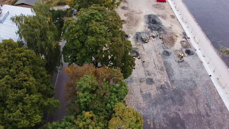 workers working in archeological digsite on riverside in kaunas city, aerial view