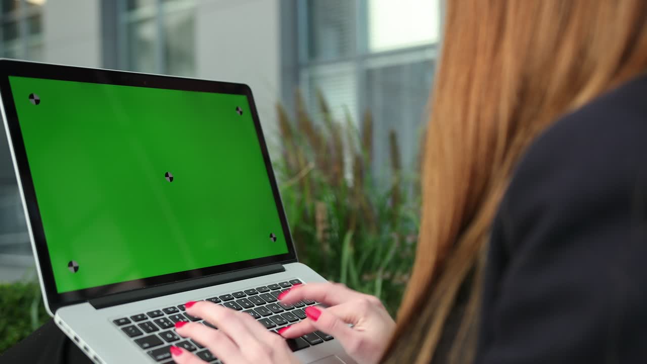 las manos de las mujeres trabajando en la computadora portátil fuera de la pantalla verde de la oficina.