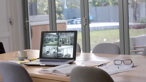 laptop on dining table showing four home security camera views, slow motion