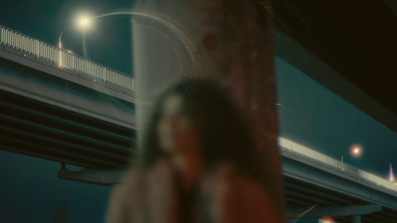 Young Woman in Fluffy Jacket Standing under Urban Overpass at Night