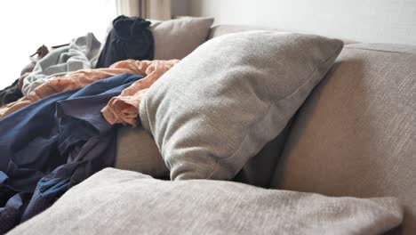 messy sofa with clothes pile