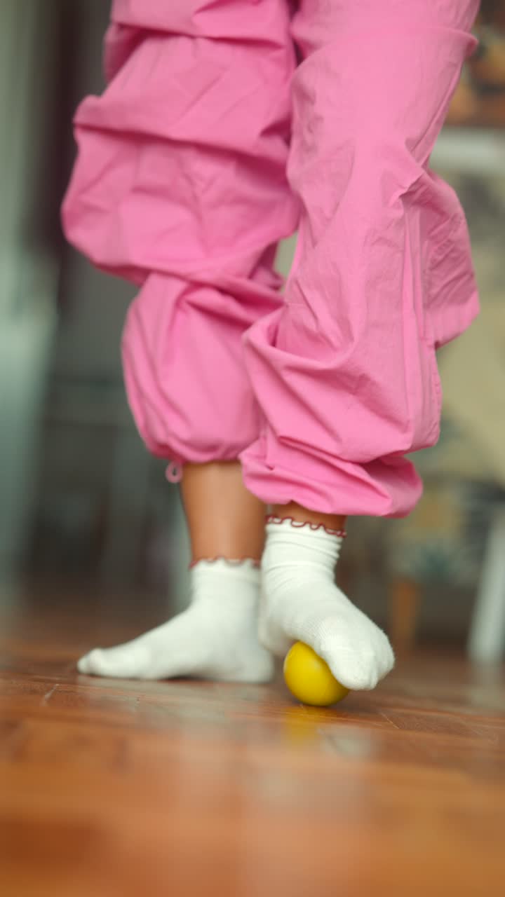 Child in Pink Pants and White Socks Playing with a Yellow Ball