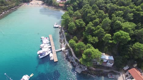 descending aerial view from drone approaching the blue water of the adriatic with boats at a wooden dock of a marina on hvar island, croatia