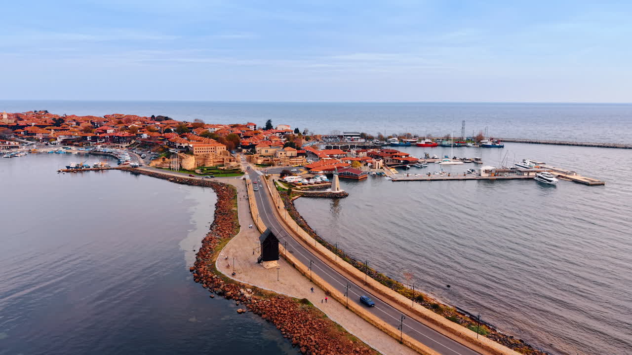 En havn set ovenfra med forskellige både fortøjet. Havnefronten har bygninger og et fyrtårn langs kystlinjen