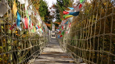 Acera-Del-Himalaya-En-Lo-Profundo-De-La-Naturaleza-Skywalk-Construcción-De-Madera-De-Pase-Golpeado-Por-Fuertes-Vientos-Troncos-De-árboles-Banderas-De-Colores-Durante-Un-Soleado-Día-De-Otoño-Capturado-En-El-área-De-Radhost-Pustevny-Cámara-Lenta-4k-60fps