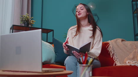 Adult-girl-student-study-at-home-on-laptop-computer-making-conference-video-call-talking-to-webcam