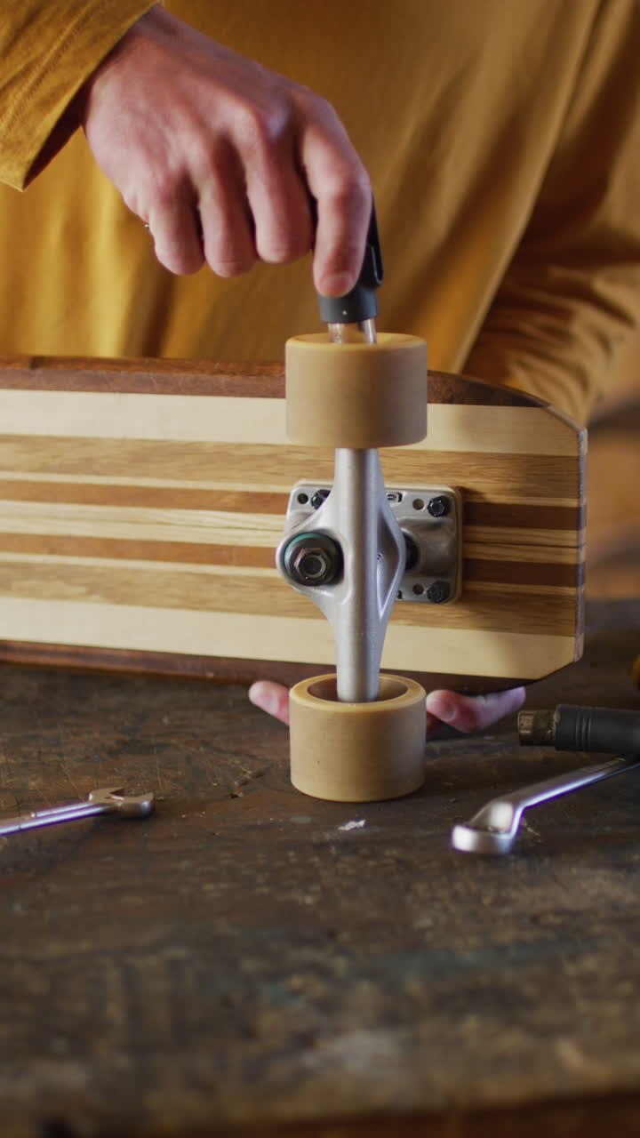 Video verticale delle mani di uno skateboarder caucasico (uomo) che aggiusta lo skateboard