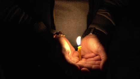 woman holding lighted burning candle in her hands on easter at midnight, as orthodoxic sign and symbol of christian faith