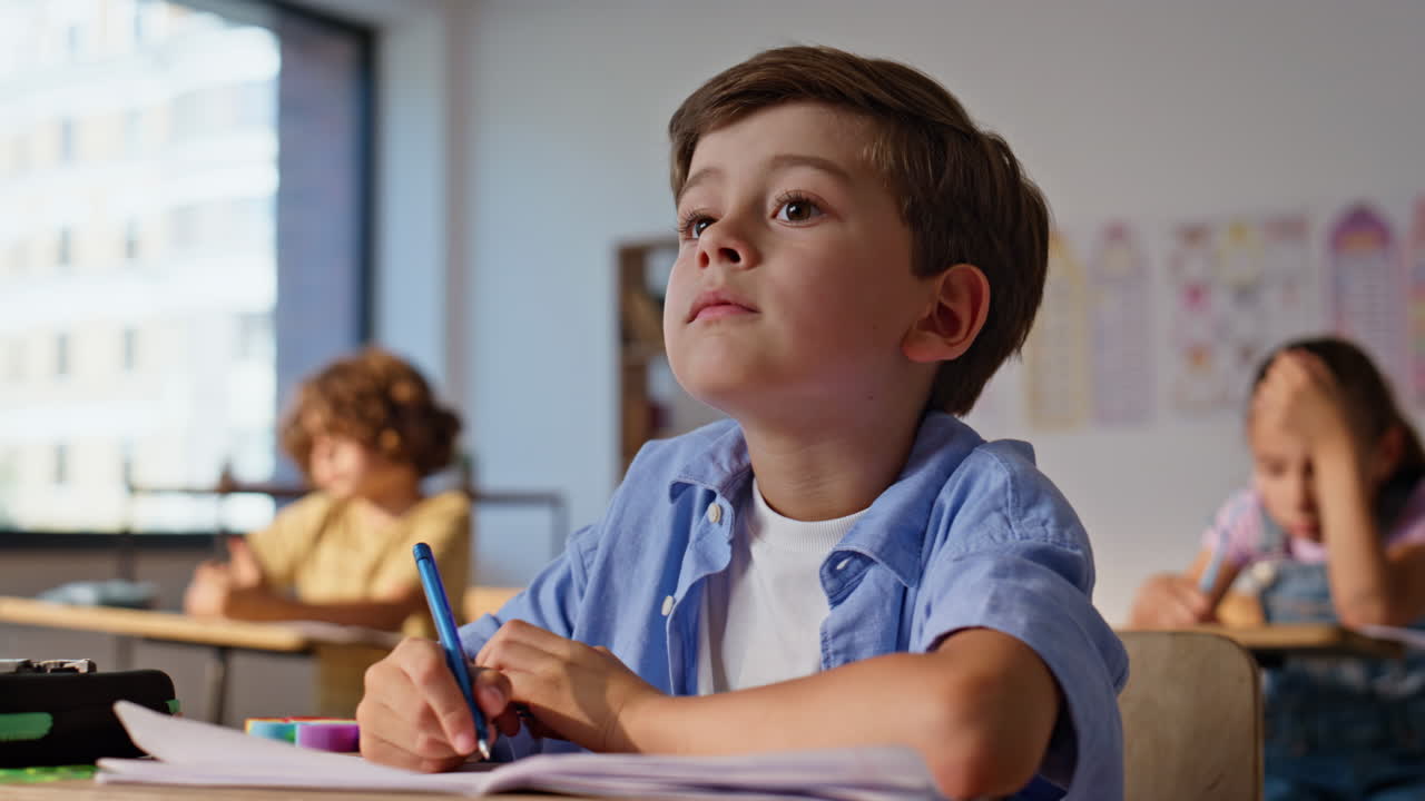 Smart schoolboy listening teacher making notes in copybook closeup. Cute boy