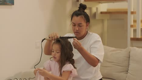 madre embarazada peinando el cabello de su hija en casa