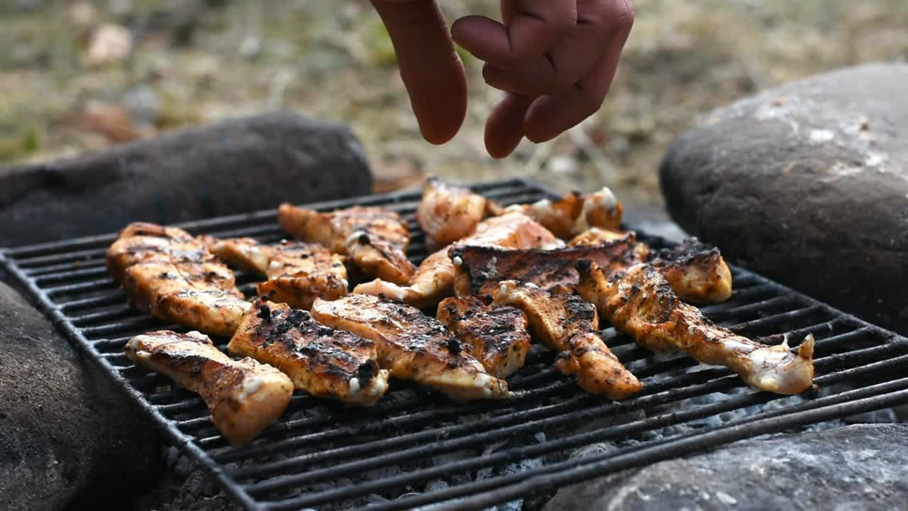 voltear los filetes de pollo sazonados a la parrilla con la mano.