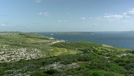 llanuras verdes de la isla de gozo cerca del mar mediterráneo con la isla de comino en el fondo