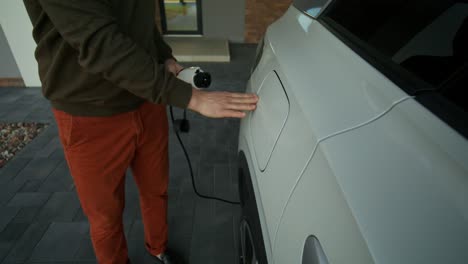 hombre cargando coche eléctrico en casa