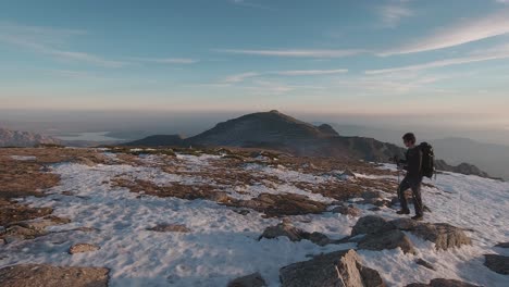 Vista-Lateral-De-Un-Joven-Excursionista-Con-Mochila-Y-Bastones-De-Trekking-En-Las-Nevadas-Montañas-De-Guadarrama,-Madrid,-España