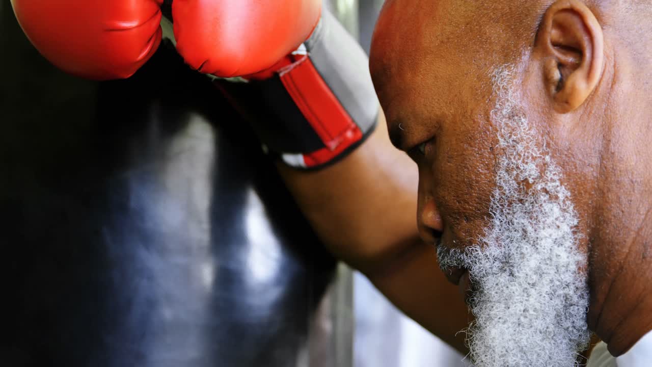 Pugile anziano stanco appoggiato al sacco da boxe 4k