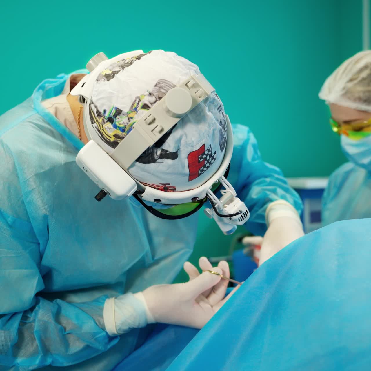 Operating room of surgical procedure. Specialist in medical uniform and surgical flashlights on head perform an operation. Assistant helps the surgeon in clinic.