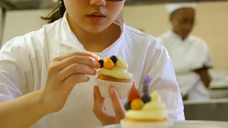 Female-chef-garnishing-muffins-in-kitchen-4k