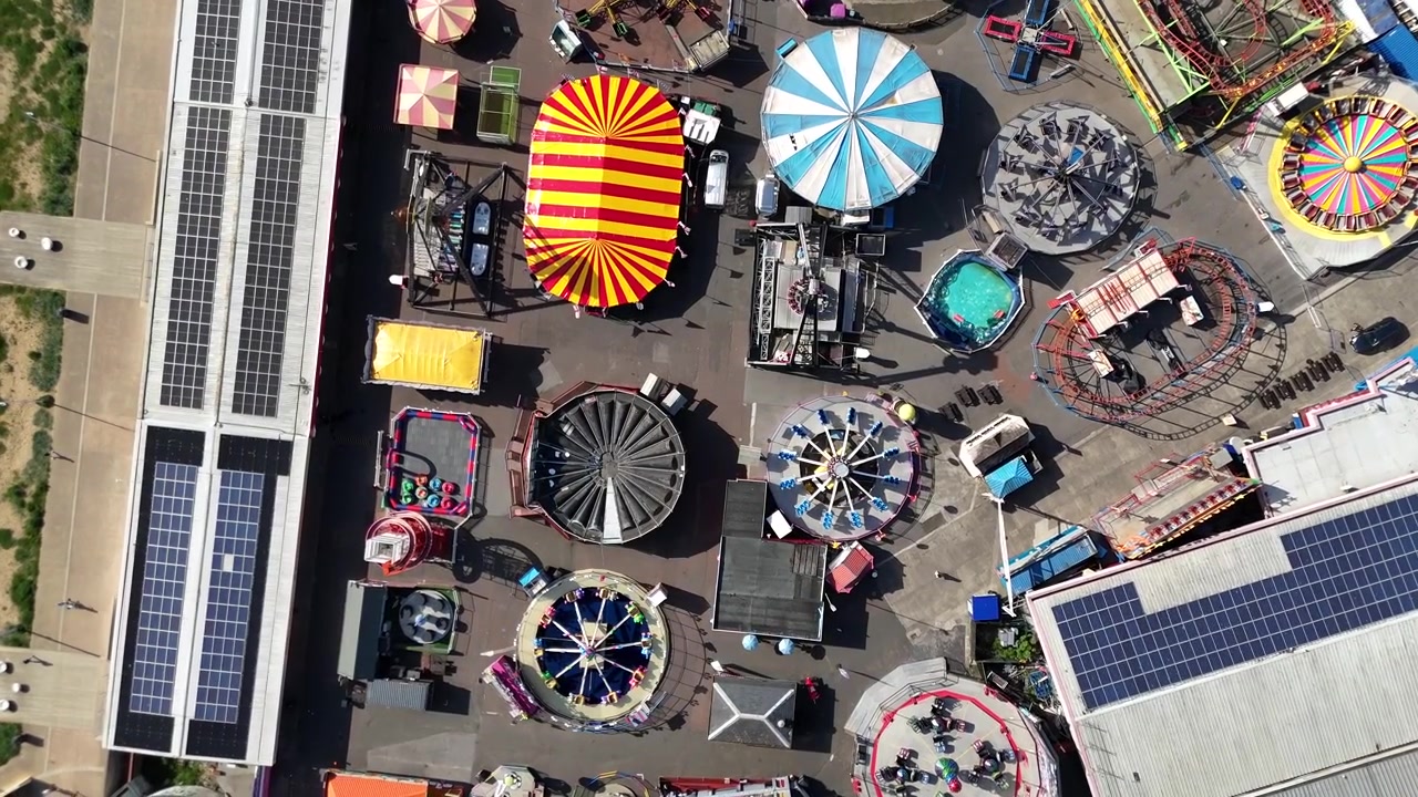 Vista aérea de drone de atrações e brinquedos coloridos de parque de diversões.