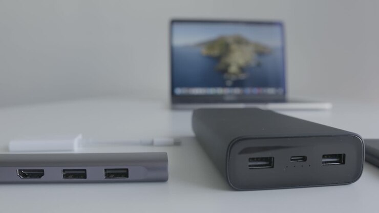 Bærbar computer, powerbank og hub på et bord