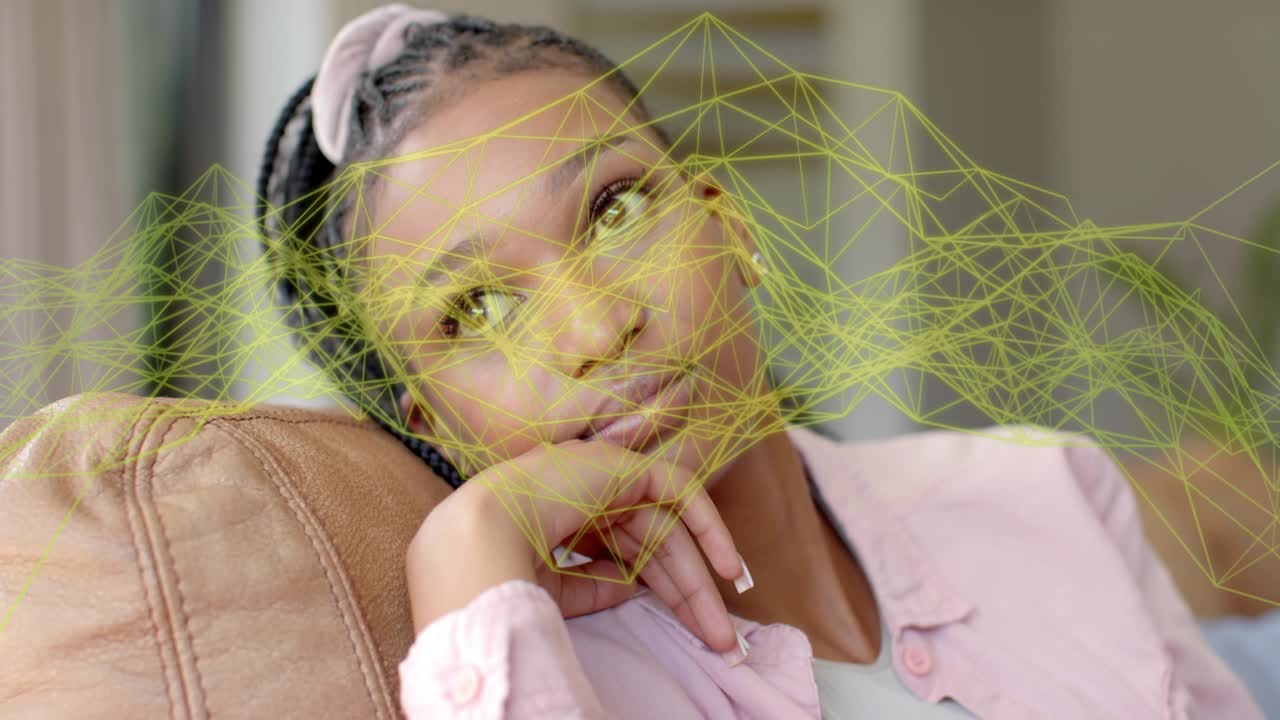Woman reclining on couch, hand at chin, watching yellow mesh sweeping across face, mapping for tech
