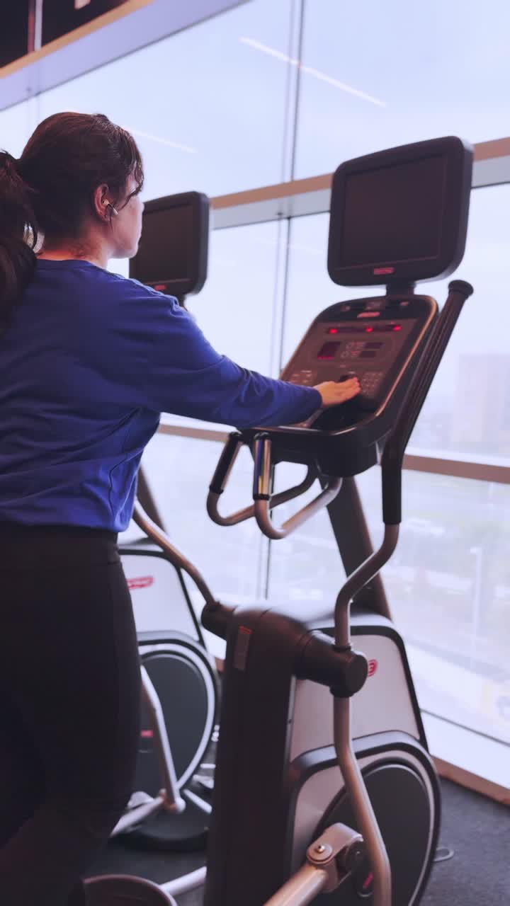 Young woman working out on elliptical trainer in gym