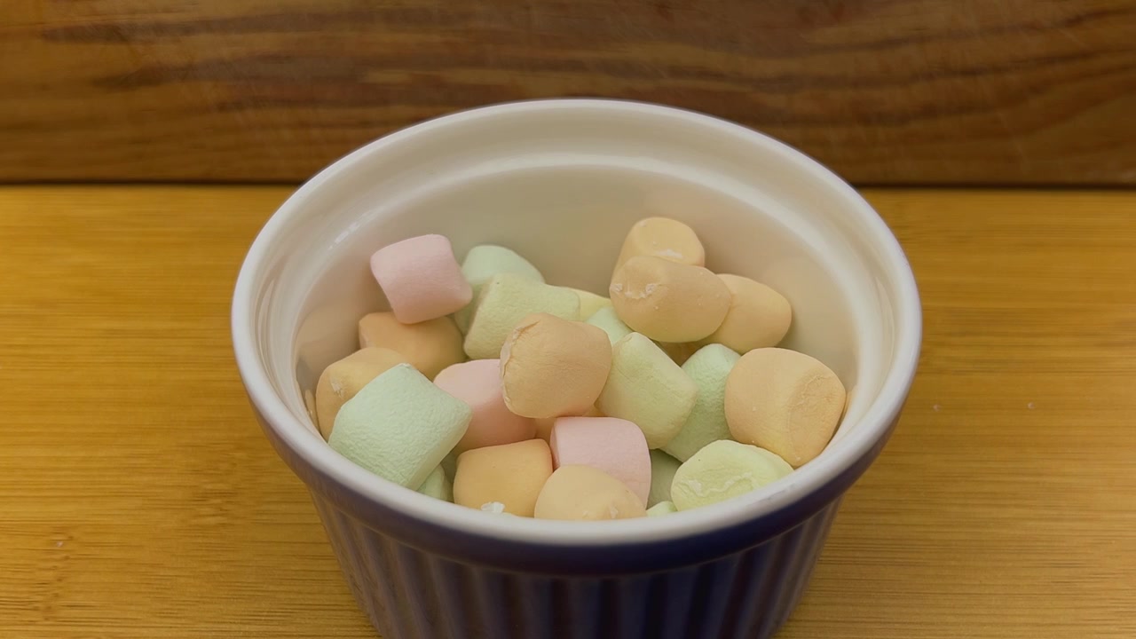 Tatlı atıştırmalık veya tatlı hazırlığı için seramik kaseyi dolduran renkli marshmallowlar, yumuşak şekerleme dokusunu, pastel renkleri ve şekerli lezzeti sergiliyor.