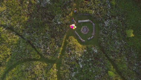 drone shot of two female friends camping at music festival running through field with balloons