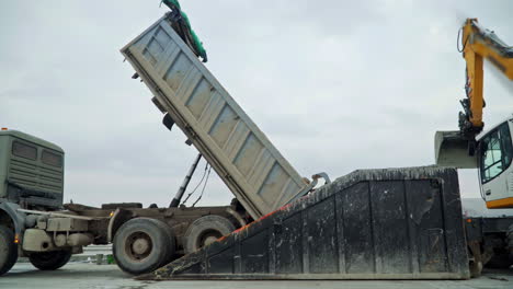 Dump-truck-unload-cargo-into-special-container,-side-view