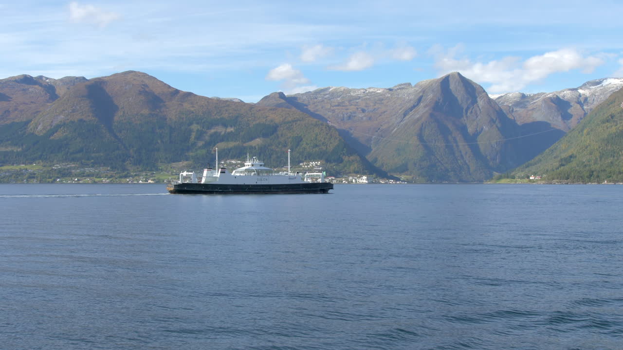 un ferry que pasa por un fiordo con hermosas montañas al fondo, a cámara lenta