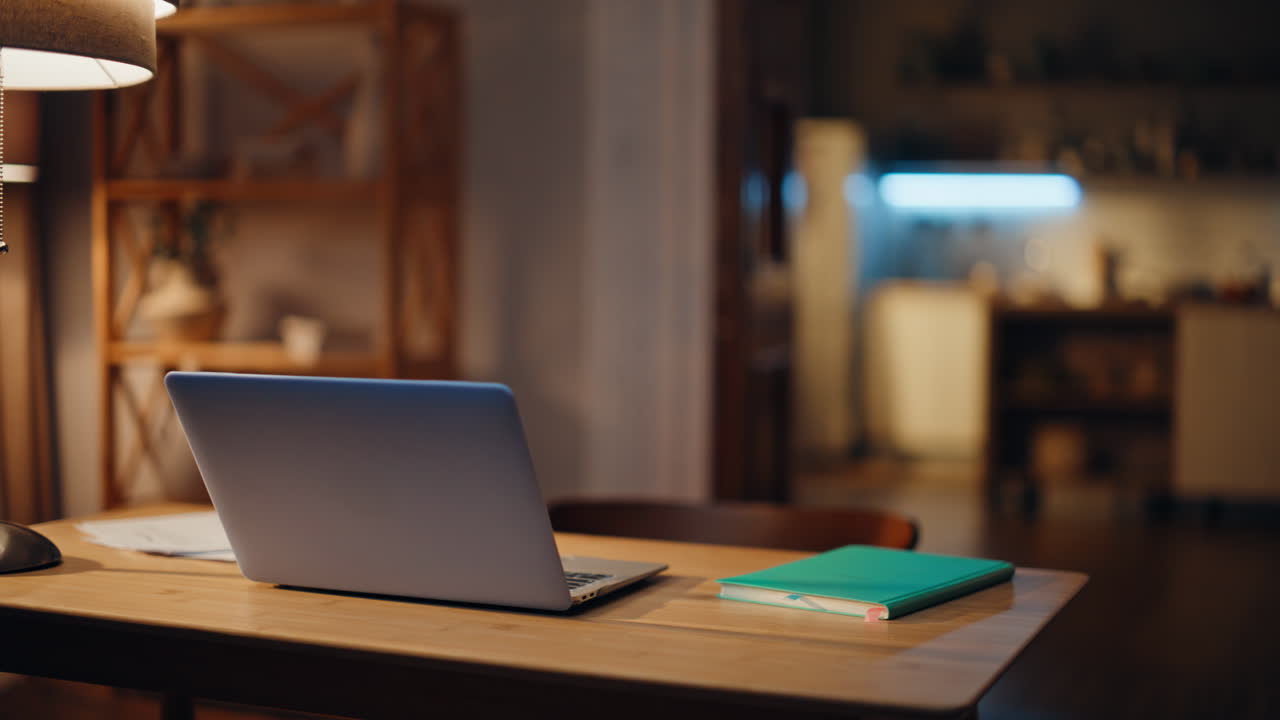 Laptop standing desk empty apartment room at lamp light closeup. Open computer