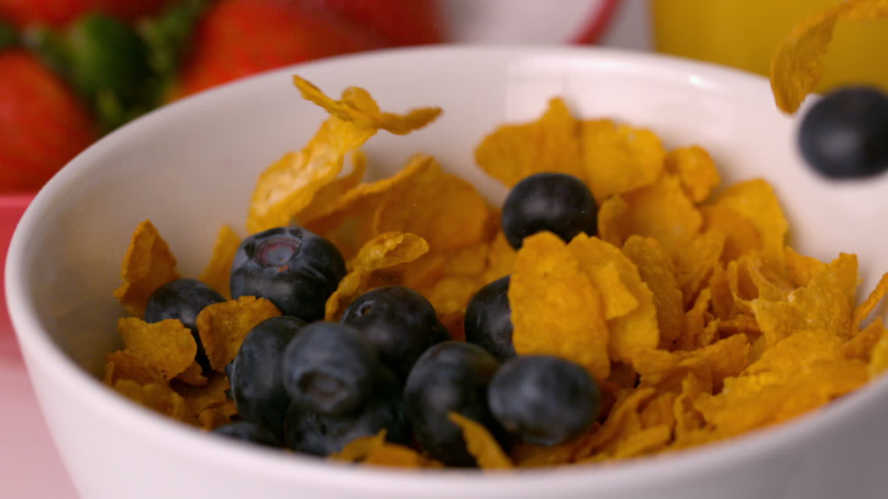 Mirtilli che si versano in una ciotola di cereali sul tavolo della colazione