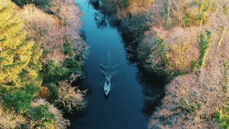 aerial shot boat driving along river in autumn