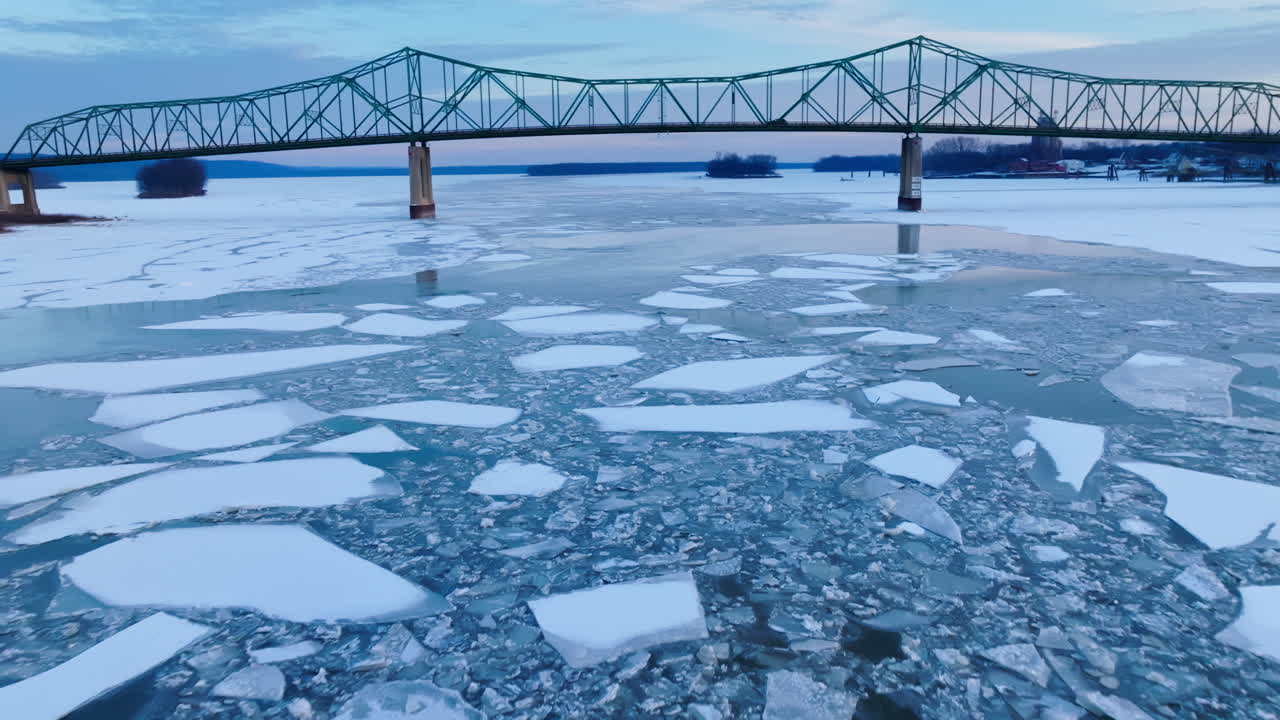 A breathtaking drone's-eye view of colossal ice chunks in the water with bridge in view