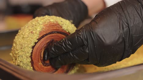 donut de croissant de pistacho siendo decorado rodando sobre crema y pistacho goteando