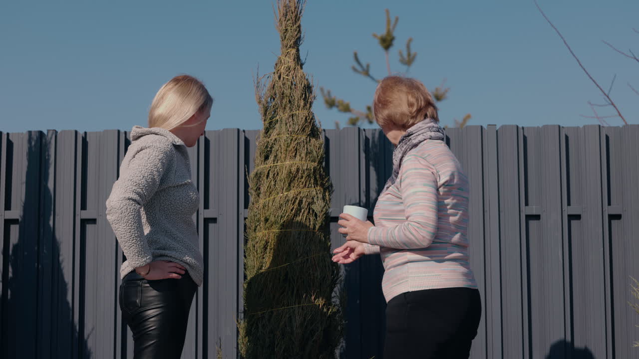 две женщины сажают дерево в саду