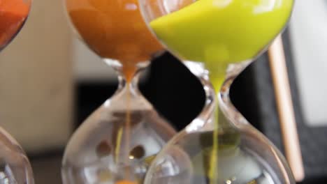 macro shot of three colorful hourglasses - red and yellow sand falling