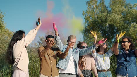 slow motion of happy young people throwing colorful powder paint during indian holi festival outdoors in park