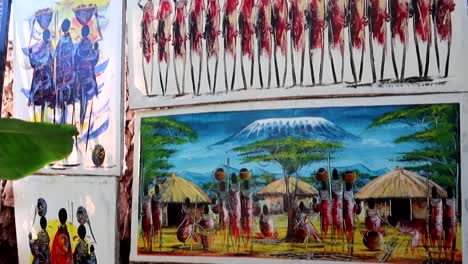 Beautiful-Tinga-Tinga-paintings-figuring-animals-and-local-tribe,-tilt-up-reveal
