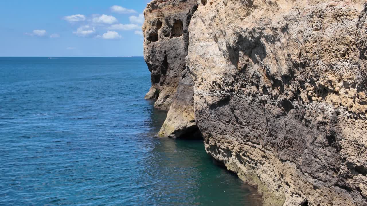 Eroded rocky cliffs meet the calm blue sea in Algar Seco Portugal