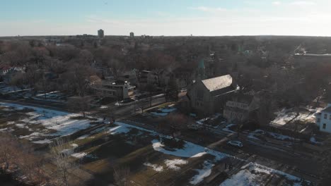 Aerial-footage-of-cars-driving-on-a-road-in-a-nice-neighborhood-during-sunset